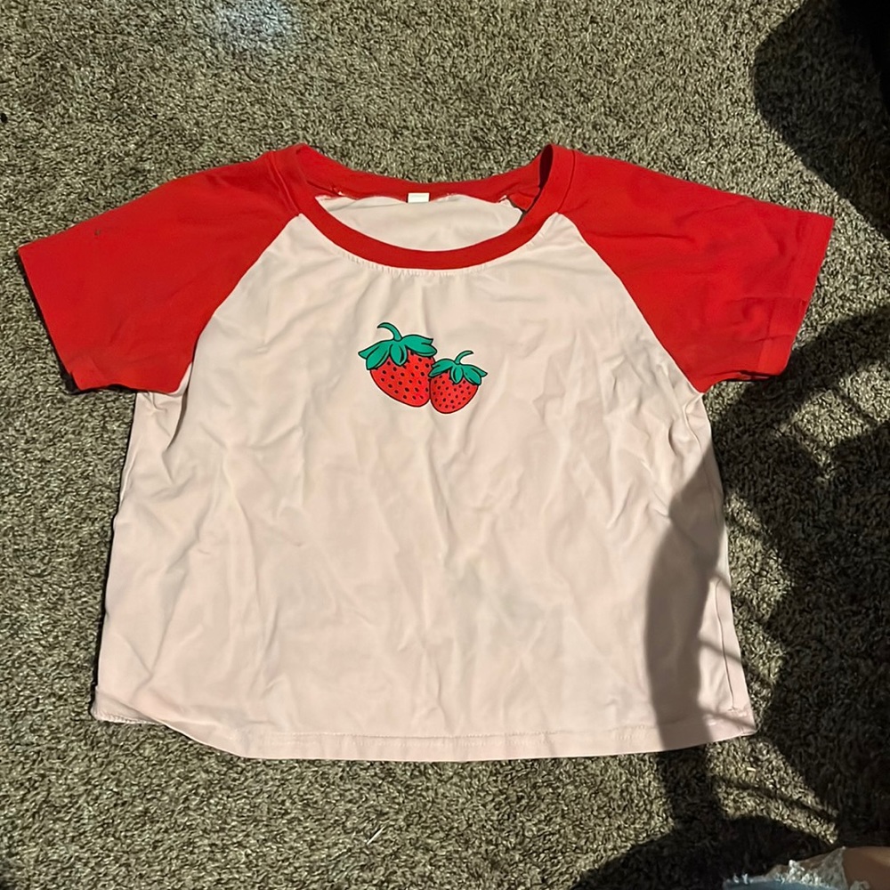 This a cute crop top shirt with strawberries. Colors pink and red.